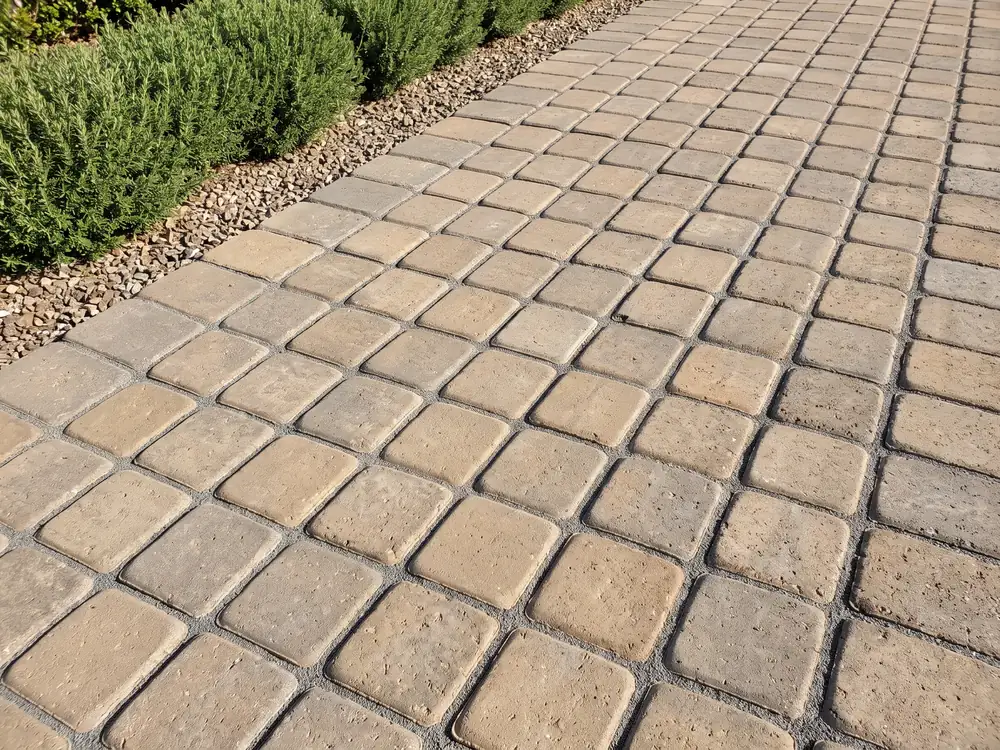 Tumbled tan concrete pavers with rounded edges and joints filled flush with gray joint sand